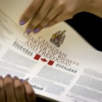 photo of two hands holding a printed copy of the Canadian Charter of Rights And Freedoms