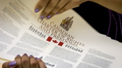 photo of two hands holding a printed copy of the Canadian Charter of Rights And Freedoms